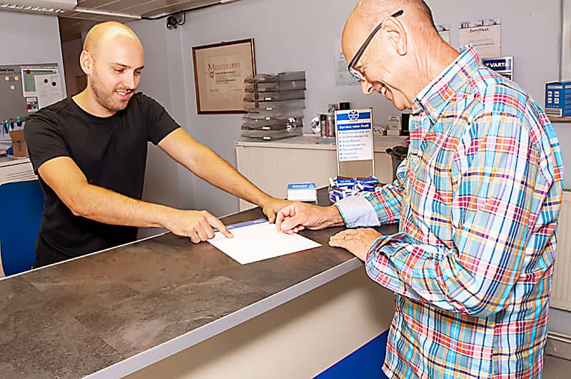 Konstantin K&uuml;mmeth im B&uuml;ro mit einem Kunden bei der Abholung seines Autos.